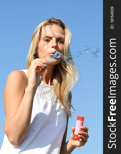 Beautiful blond woman playing with soap bubbles