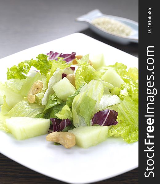 A salad made of lettuce,cabbage,melon and cashius peanuts. A salad made of lettuce,cabbage,melon and cashius peanuts