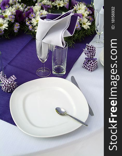 Purple place setting with white cutlery and white and purple daisies. Purple place setting with white cutlery and white and purple daisies