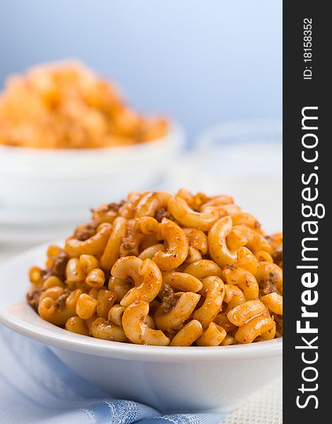 Macaroni with tomato meat sauce. Blue background. Shallow depth of field. Macaroni with tomato meat sauce. Blue background. Shallow depth of field.