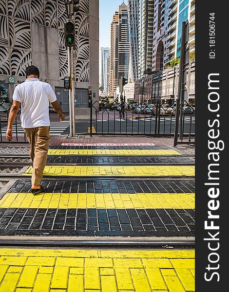 Dubai street scene. Man walking a cross the street