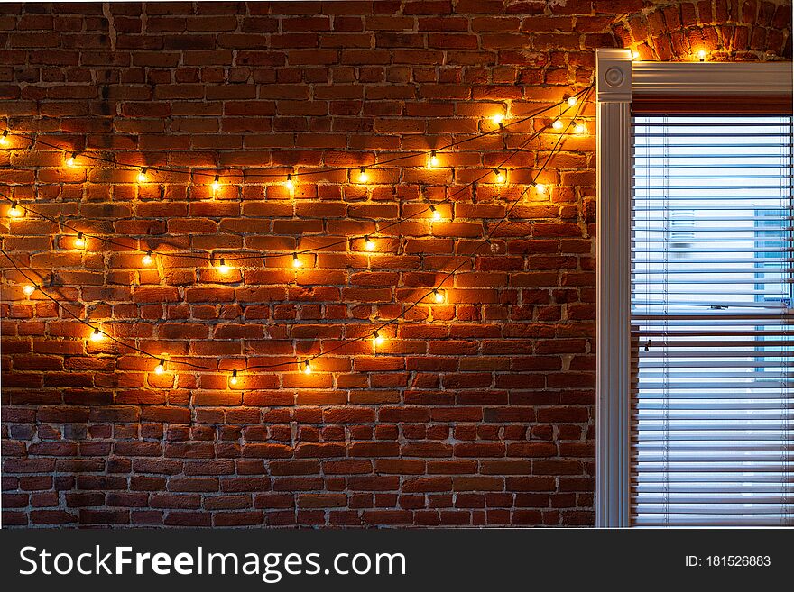 The string of vintage lights bulbs inside at night, lights on a brick wall background, selective focus