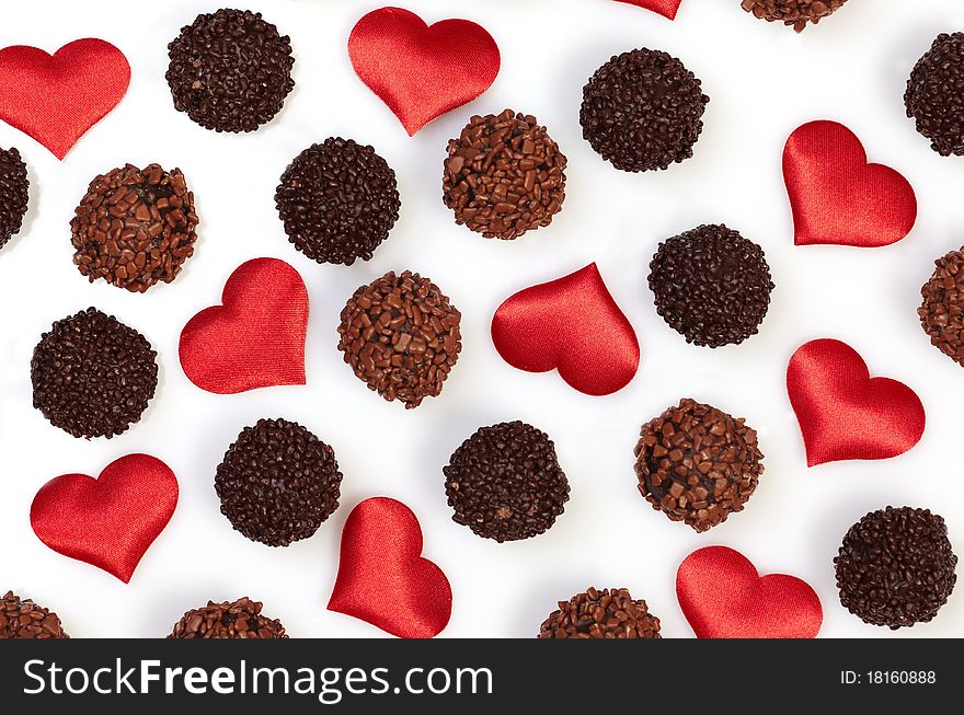 Chocolate truffles and heart shapes on white background