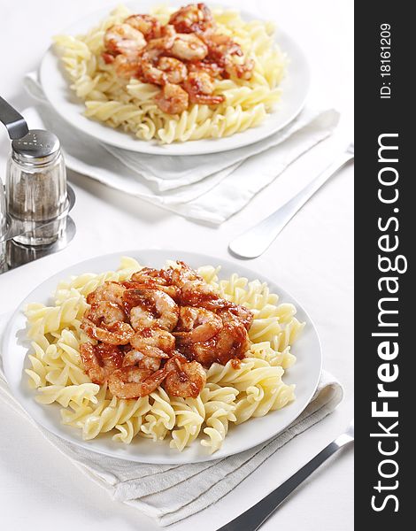 Two plates of pasta with tomato and shrimps