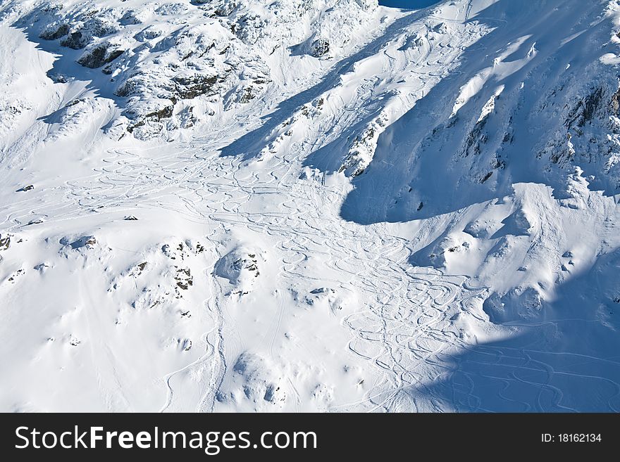 Many ski and snowboard tracks on a steep mountain slope. Many ski and snowboard tracks on a steep mountain slope.