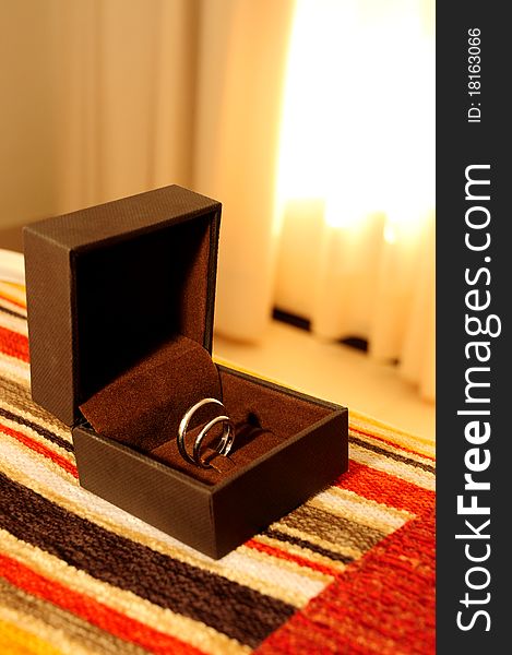 Wedding rings, in a brown box, on the bed. Wedding rings, in a brown box, on the bed