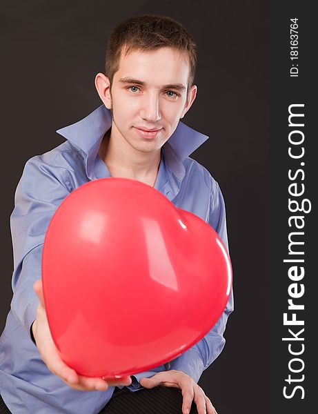 Young guy holding a red heart-shaped balloon