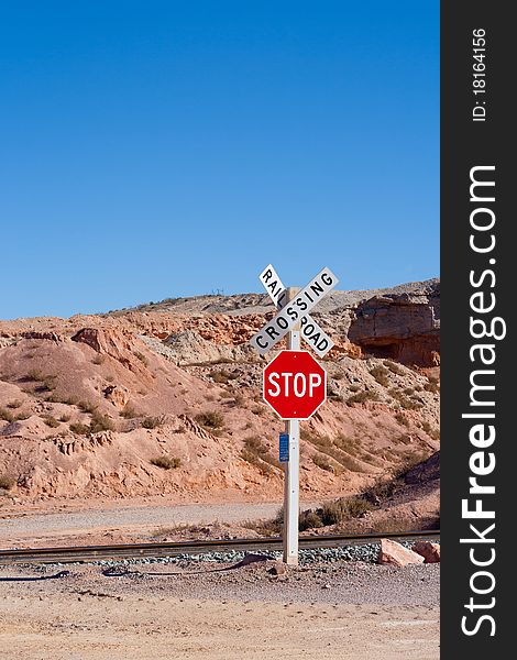 A lonely railroad crossing with a stop sign and a desert background. A lonely railroad crossing with a stop sign and a desert background.
