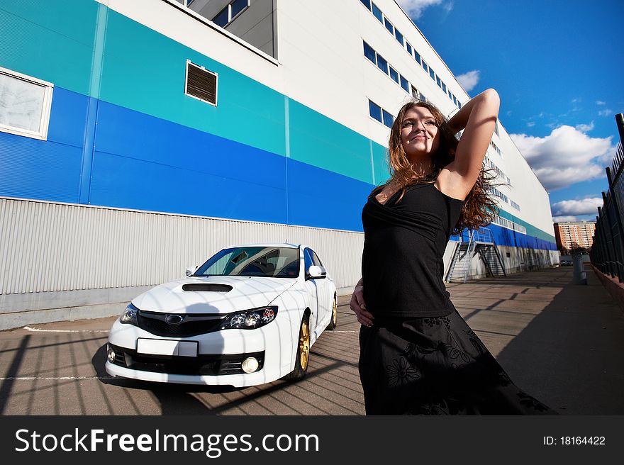 Beautiful girl and stylish white sports car on the background industrial building