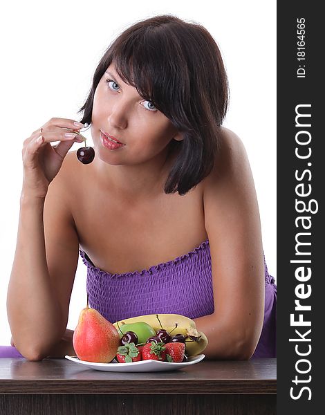 Cheerful tanned woman eating fruit and berrie. Cheerful tanned woman eating fruit and berrie