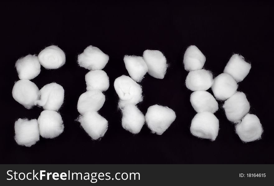 The word 'Sick' written with cotton balls. Isolated on black.