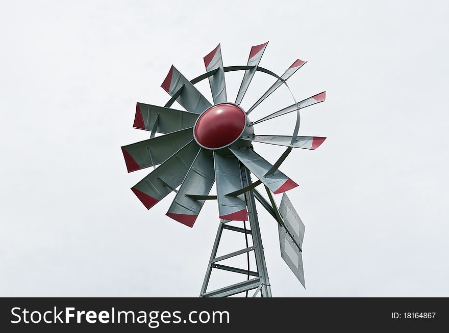 A small windmill spins and generates electricity with a grey sky in the background. A small windmill spins and generates electricity with a grey sky in the background.
