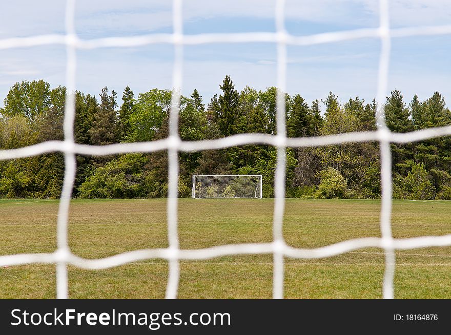 An outdoor soccer field viewed through the mesh of one of the nets.