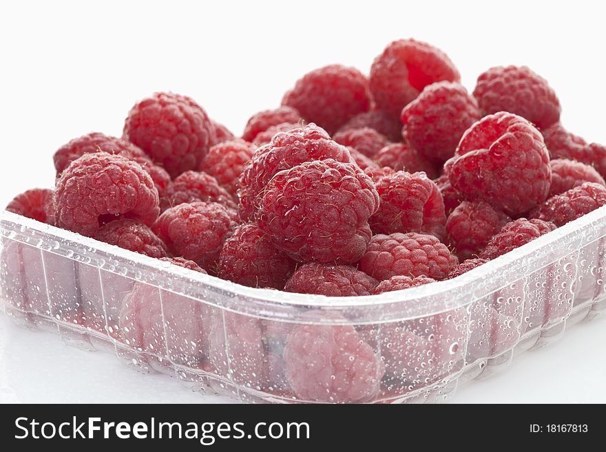 Fresh ripe raspberries in a platter on a white background