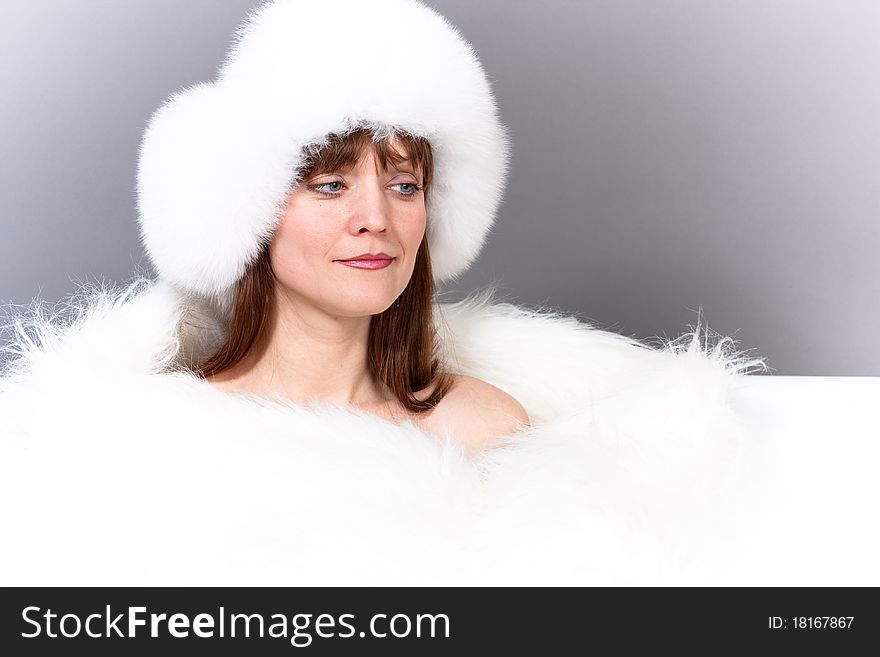 The charming young woman in a cap from white fur and a fur cape. The charming young woman in a cap from white fur and a fur cape