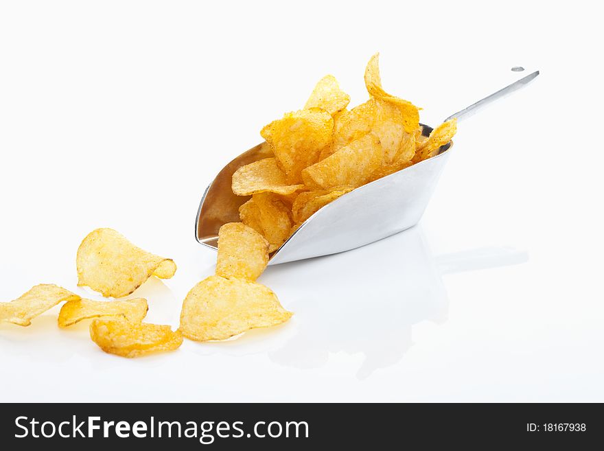 Golden potato chips on and in front of a shovel isolated on a white background