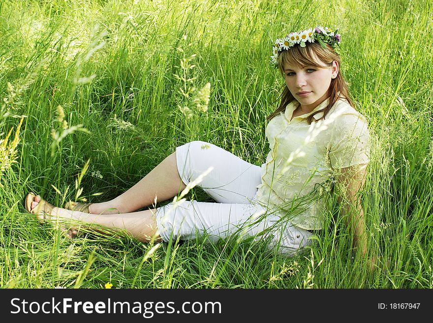 Young girl into the wreath on the grass. Young girl into the wreath on the grass