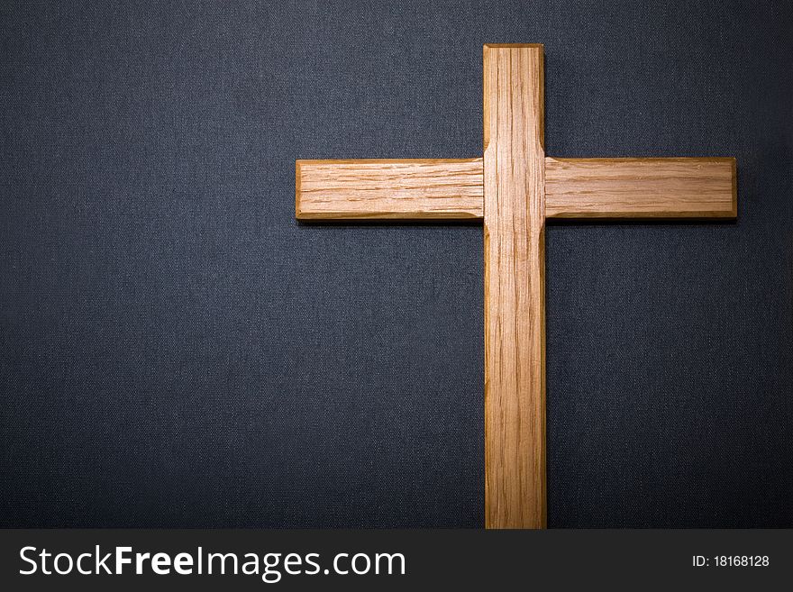 Wooden cross against dark grey background with copyspace