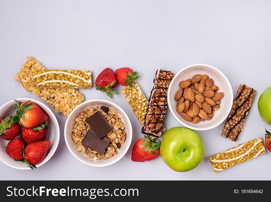 Bowls with Granola or Muesli Bowl with Strawberry and Almond Muesli Bars Green Apples Blue Background Healthy Diet Breakfast Top View Flat Lay.