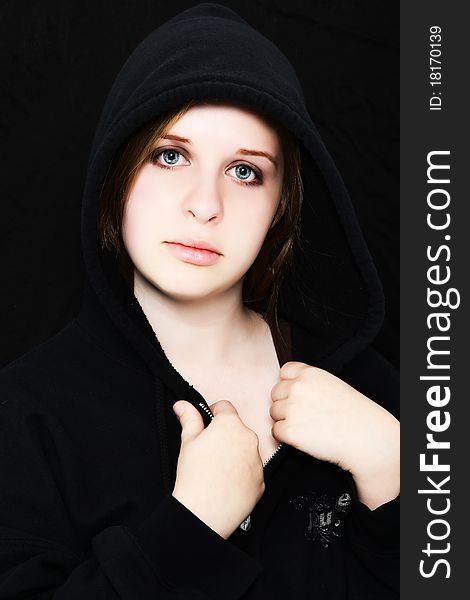 Beautiful 18 year old teenager in black hoodie over black. Pale skin. Serious expression. Beautiful 18 year old teenager in black hoodie over black. Pale skin. Serious expression.