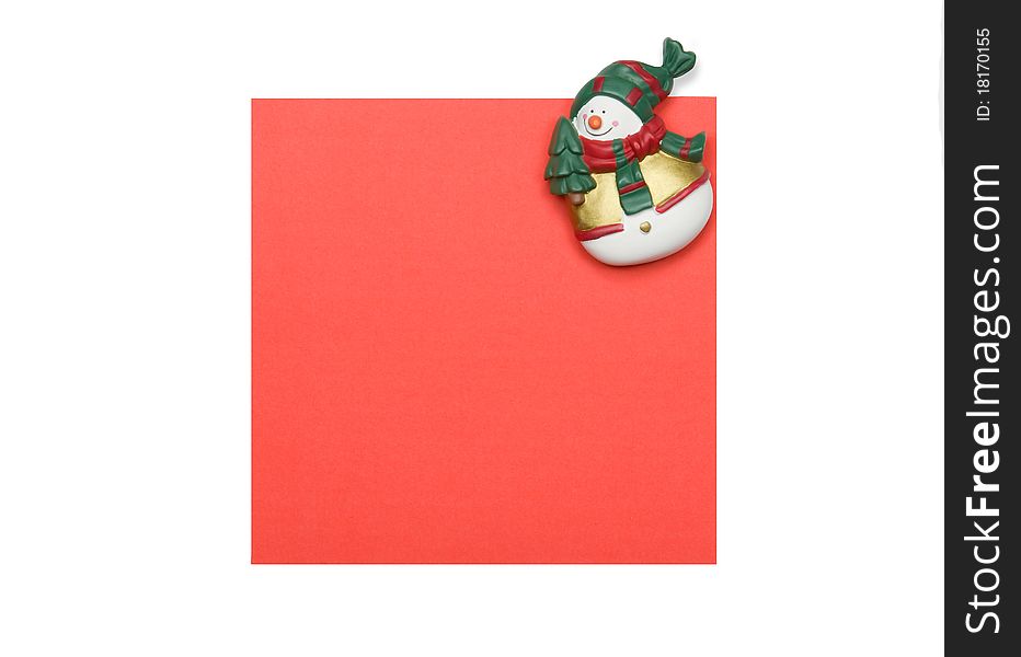 Snowman refrigerator magnet on a red paper sheet isolated over white. Snowman refrigerator magnet on a red paper sheet isolated over white