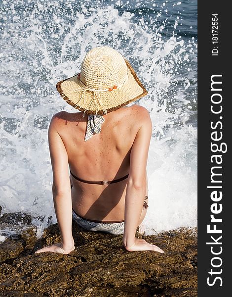 Woman with hat sunbathing on rocks