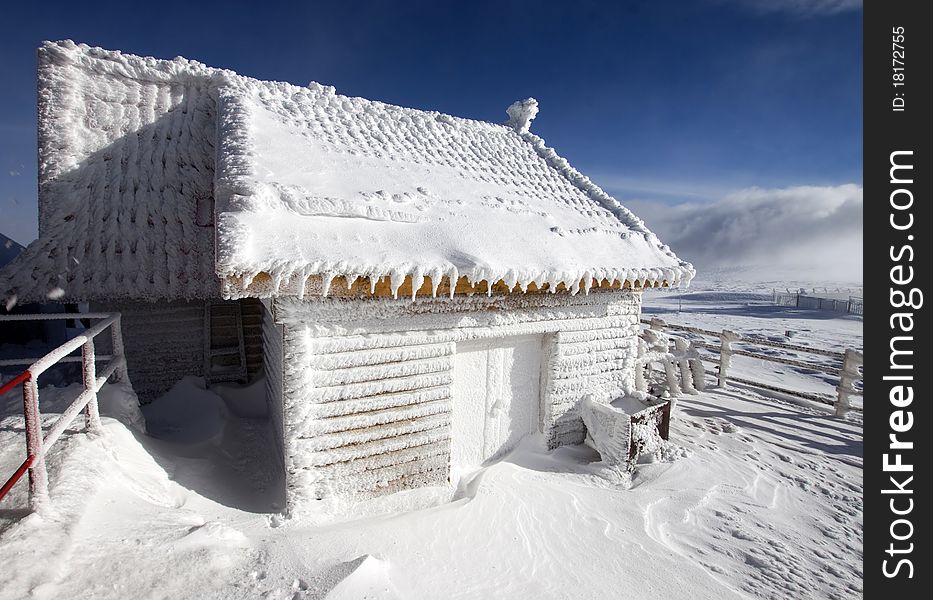 Wooden cottage covered with snow in the mountains