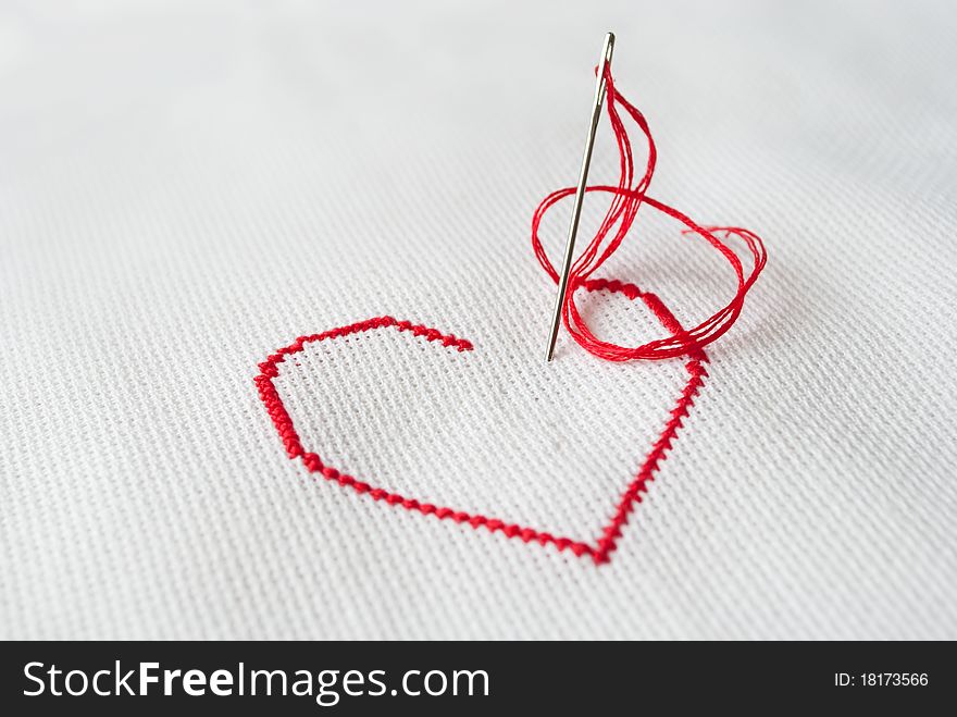 Embroidered red heart on white with needle sticked in canvas. Embroidered red heart on white with needle sticked in canvas