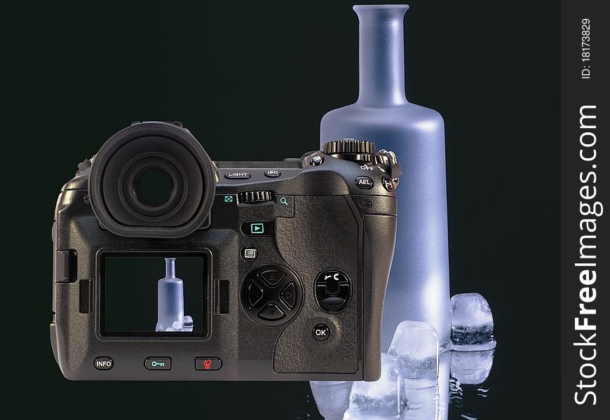 The Image shows a photomontage of a digital camera over an image which shows a bottle and some ice cubes over black