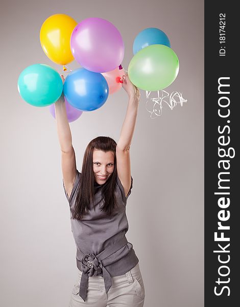 Young happy girl with balloons over gray. Young happy girl with balloons over gray