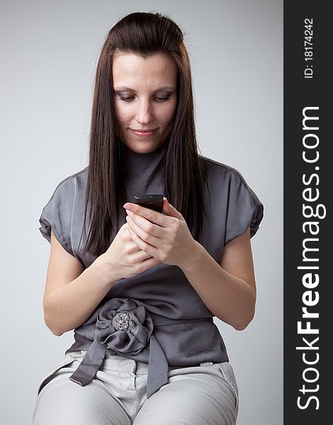 Young caucasian woman in gray dress using a mobile phone. Young caucasian woman in gray dress using a mobile phone