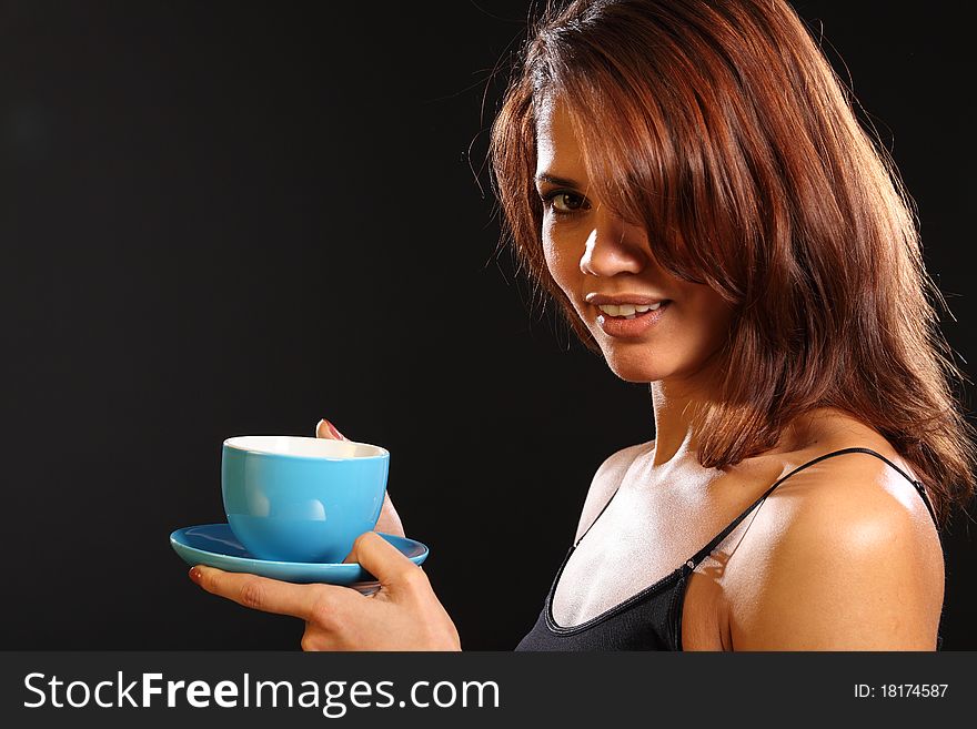 Portrait of a beautiful smiling young ethnic woman holding a cup of tea. Cup and saucer are blue. Portrait of a beautiful smiling young ethnic woman holding a cup of tea. Cup and saucer are blue.