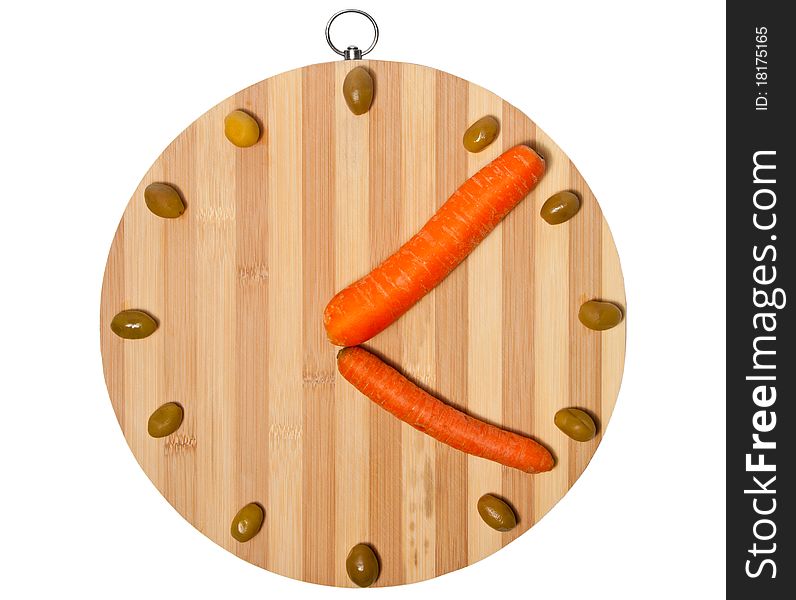 A clock made of carrots and olives on a bamboo board, isolated on white. A clock made of carrots and olives on a bamboo board, isolated on white