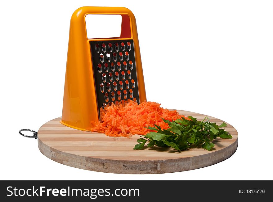 A pile of grated carrots and parsley on a bamboo kitchen board isolated on white