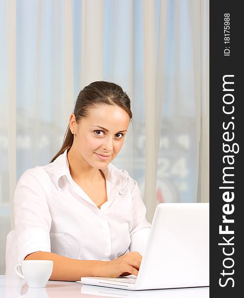 Young business woman working on laptop in white interior