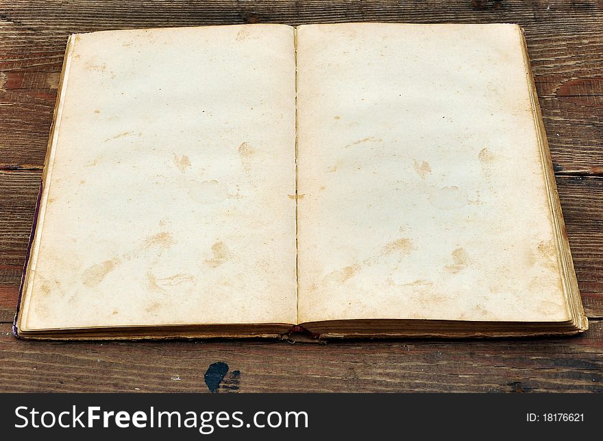 Old book with blank yellow stained pages on wood background