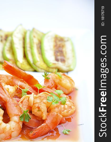 Shrimps in tomato sauce with rice and zuchinni on white plate and background.