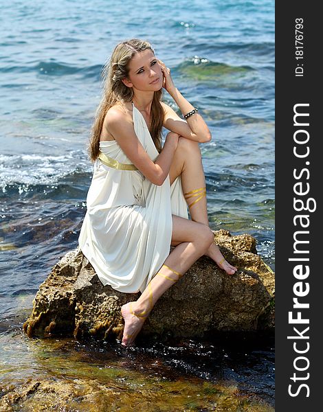 Shot of Attractive young woman  sitting   on the stone in the see
