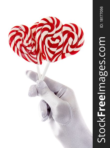 Hand in a white glove holding candy in the shape of a heart. Hand in a white glove holding candy in the shape of a heart