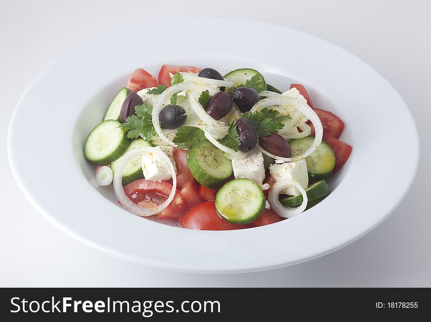 Greek salad inside a white plate and a white background