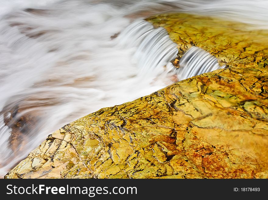 Water cascades over golden rocks in Glacier National Park, Montana. Water cascades over golden rocks in Glacier National Park, Montana.