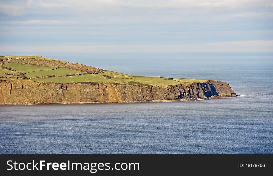 Cliffs on a coastline with flat seas on a clear day. Cliffs on a coastline with flat seas on a clear day