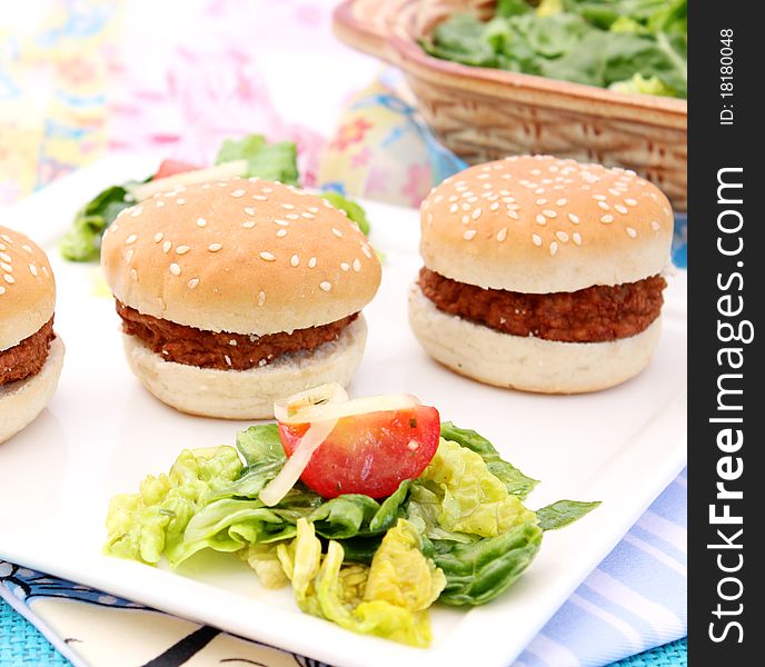 Some small burger with a salad. Some small burger with a salad