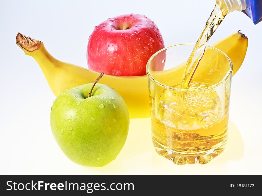Banana, green and red apples and glass filling with apple juice. Banana, green and red apples and glass filling with apple juice