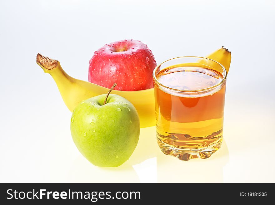 Banana, green and red apples and glass of apple juice