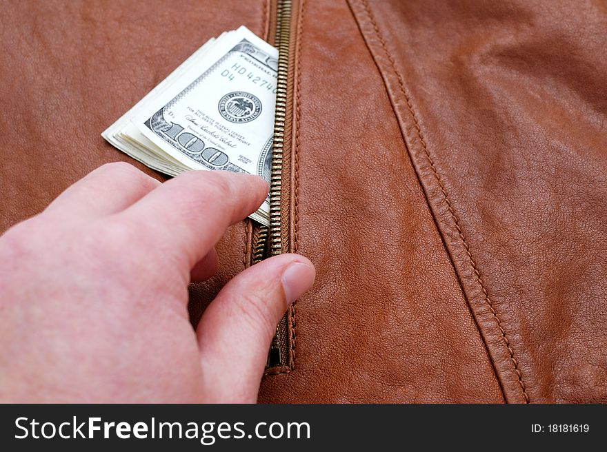 Hand taking dollars from a pocket of leather jacket. Hand taking dollars from a pocket of leather jacket.