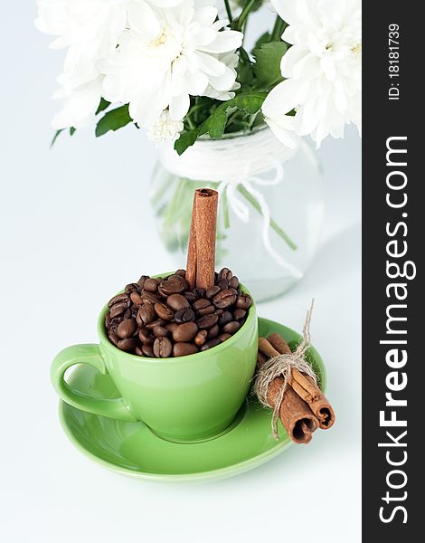 Coffee beans and cinnamon stick in a green cup