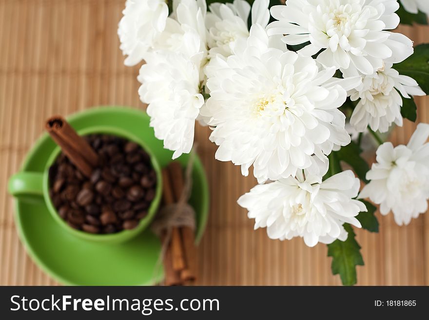 Coffee beans and cinnamon stick stand in a green cup. Coffee beans and cinnamon stick stand in a green cup