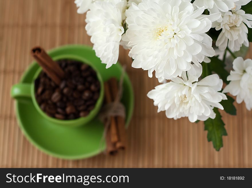 Coffee beans and cinnamon stick stand in a green cup. Coffee beans and cinnamon stick stand in a green cup