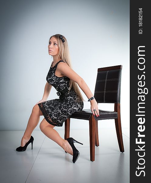 Young beautiful woman, blond girl sitting on chair, studio glamour portrait. Young beautiful woman, blond girl sitting on chair, studio glamour portrait